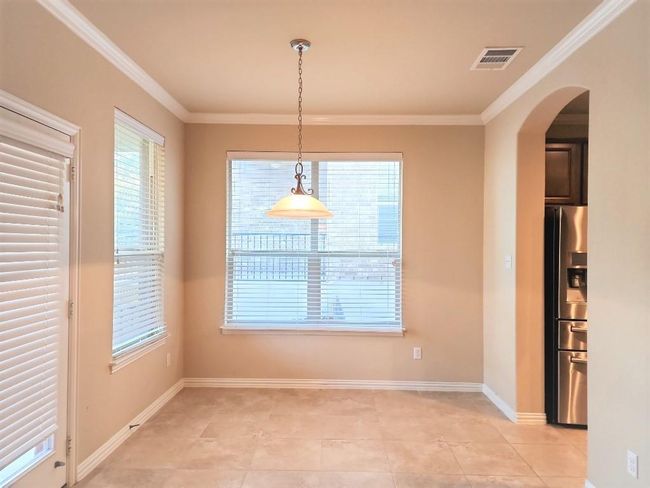 Unfurnished dining area with arched walkways, crown molding, light tile patterned flooring, and baseboards | Image 11