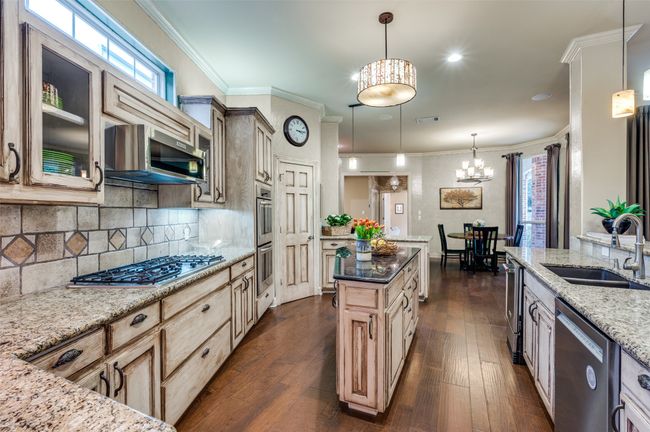 Kitchen featuring stainless steel appliances, a sink, a chandelier, light stone countertops, and dark wood finished floors | Image 9