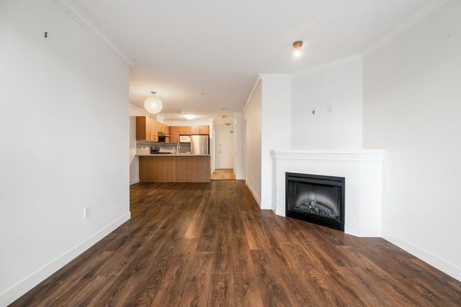 Unfurnished living room featuring dark wood-type flooring, crown molding, and a fireplace | Image 11