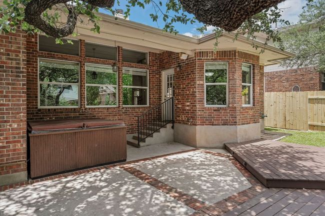 Step outside to your private backyard retreat with a covered patio, extended deck, mature trees, and lush landscaping. Unwind in the optional hot tub, perfect for Texas evenings. | Image 30