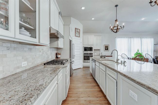 Granite countertops bring atouch of sophistication to thekitchen, while the stylishbacksplash adds visual interestand elegance. Abundant upperand lower cabinetryprovides generous storage. Asleek gas cooktop is paired witha coordinating vent hood above, offering both style andperformance for all your culinarycreations. | Image 6