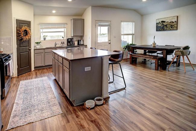 Kitchen featuring a center island, backsplash, range with gas stovetop, and gray cabinetry | Image 13