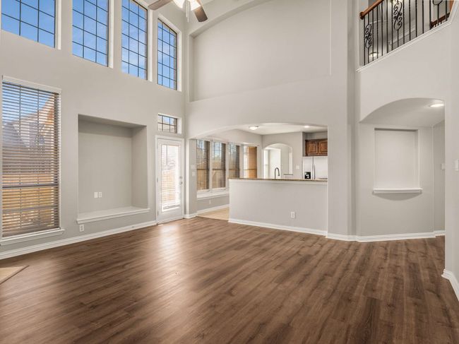 Unfurnished living room with arched walkways, baseboards, ceiling fan, and wood finished floors | Image 9