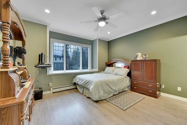 Bedroom featuring a baseboard radiator, baseboards, crown molding, light wood-style floors, and recessed lighting | Image 31