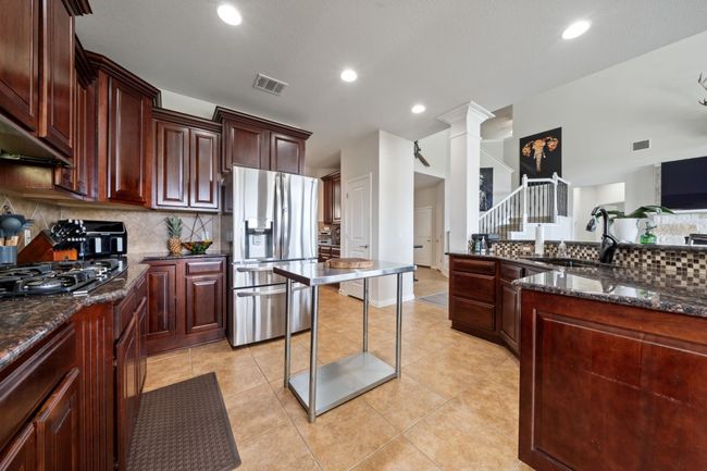 Kitchen featuring stainless steel fridge, black gas stovetop, backsplash, decorative columns, and recessed lighting | Image 10