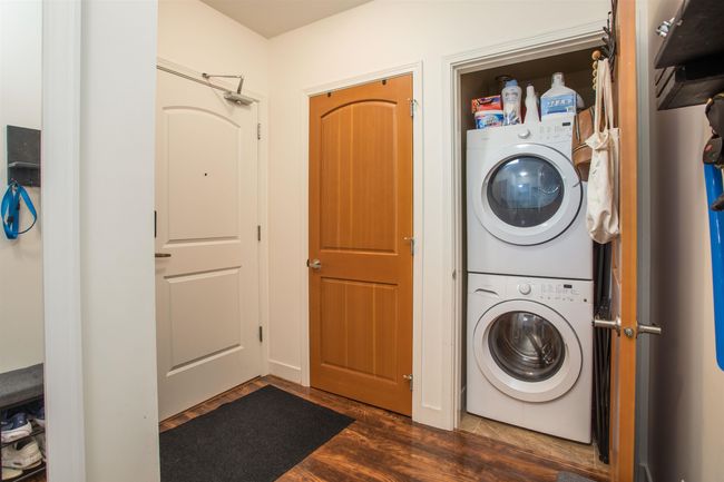 Clothes washing area featuring stacked washer / dryer, dark wood-style flooring, and laundry area | Image 22