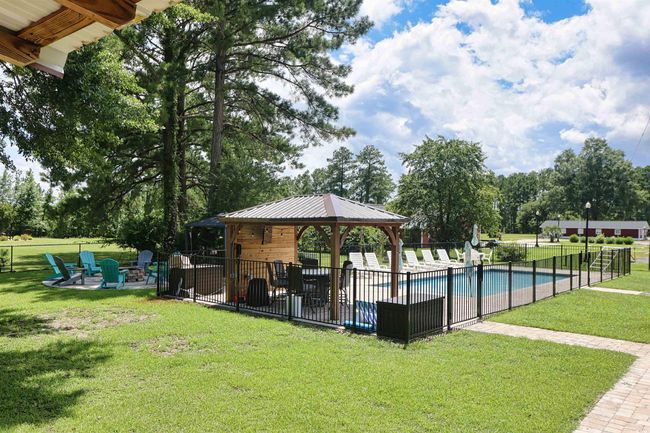 Community pool featuring a gazebo, a fire pit, a patio, and view of scattered trees | Image 28