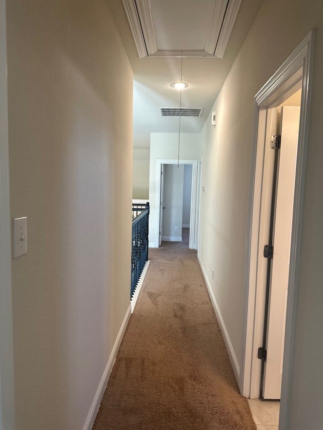 Hallway with attic access, visible vents, baseboards, and light colored carpet | Image 22
