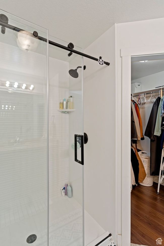 Bathroom featuring a shower stall, a walk in closet, and wood finished floors | Image 22