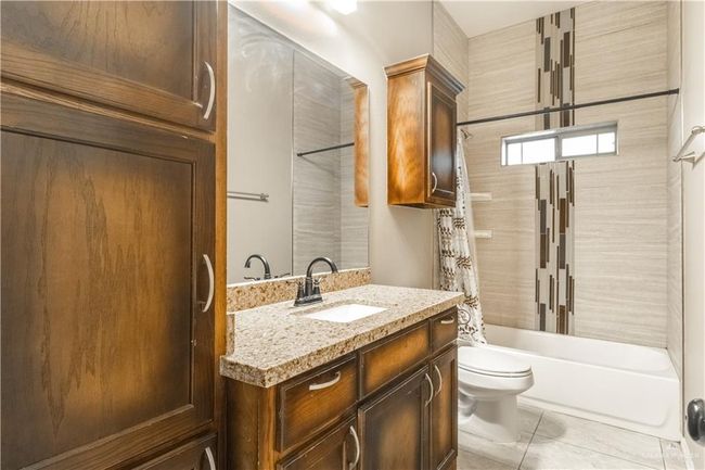 Full bathroom with toilet, shower / tub combo with curtain, vanity, and tile patterned floors | Image 7
