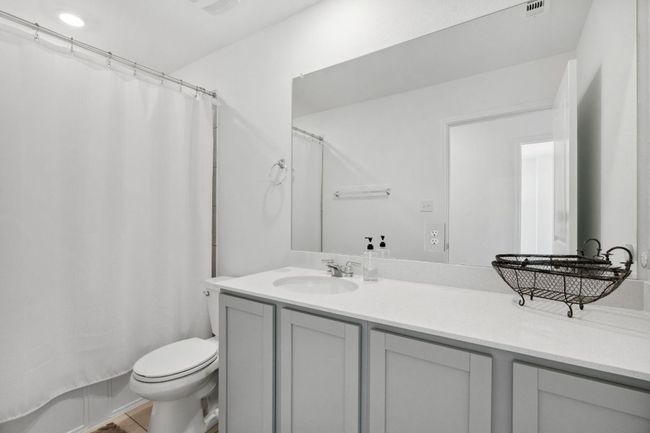 Bathroom with toilet, shower / bathtub combination with curtain, visible vents, and vanity | Image 27
