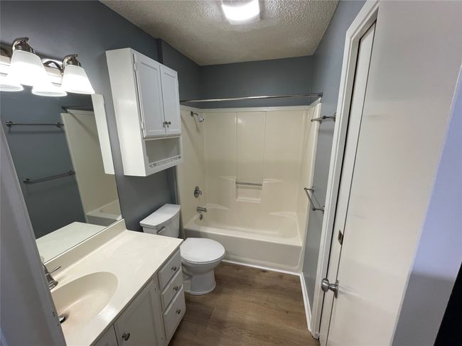 Full bathroom with a textured ceiling, vanity, shower / bath combination, toilet, and hardwood / wood-style flooring | Image 17
