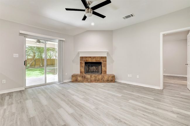 living room with a ceiling fan, wood burning fireplace, and lofted ceiling | Image 4