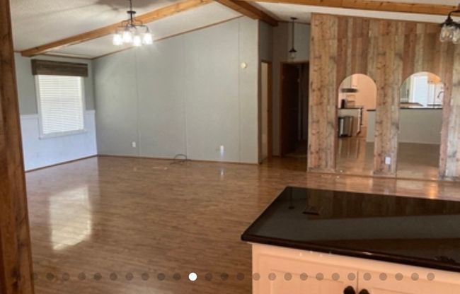 Empty room featuring arched walkways, a notable chandelier, vaulted ceiling with beams, and a wealth of natural light | Image 21