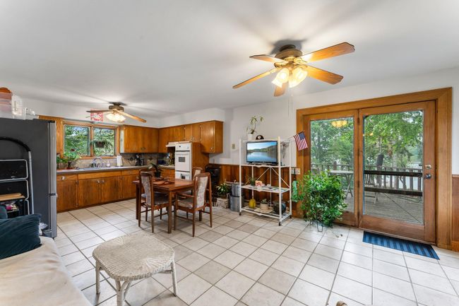 Just off the kitchen, the dining area boasts cohesive tile flooring, a ceiling fan for year-round comfort, and a built-in glass-front china cabinet. Access to the deck allows for easy indoor-outdoor entertaining. | Image 5