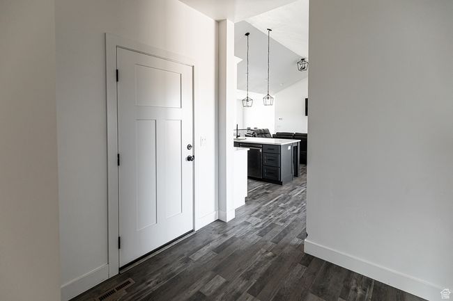 Hall featuring visible vents, baseboards, vaulted ceiling, and dark wood-type flooring | Image 20
