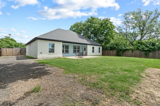 Rear view of house with brick siding, a fenced backyard, and a patio | Image 37