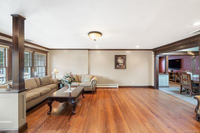 Living room with a baseboard heating unit, hardwood / wood-style flooring, and ornamental molding | Image 3