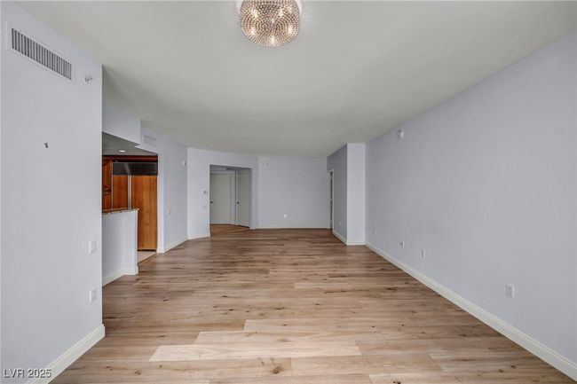 Unfurnished living room featuring light wood finished floors, baseboards, visible vents, and an inviting chandelier | Image 22