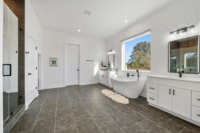 The primary ensuite luxury bath on the main level is a true retreat, offering a double vanity, walk-in closet, spa-like bath with a designer rain shower, and a freestanding tub. | Image 19