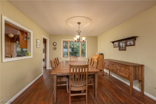 Dining space with baseboards, a notable chandelier, and dark wood-style floors | Image 25