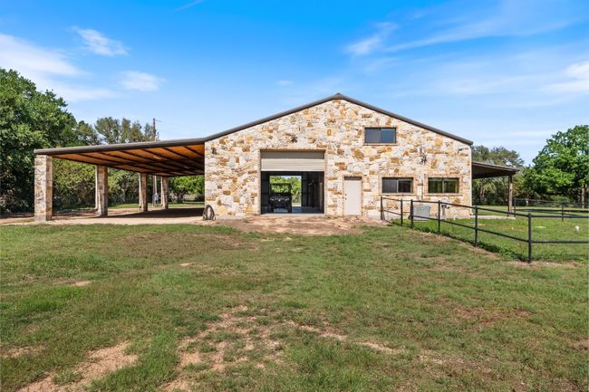 Exterior view of expansive workshop with roll up doors and additional covered parking. | Image 31