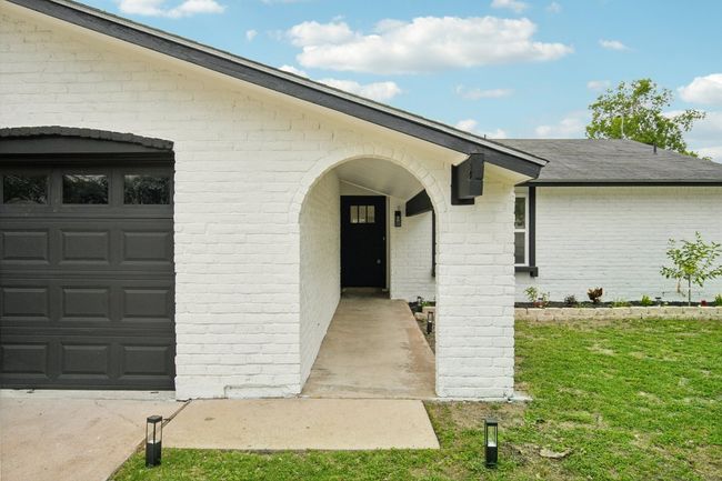 View of exterior entry featuring an attached garage, brick siding, and a shingled roof | Image 4