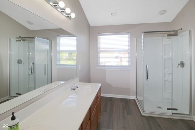 Enjoy the fresh feel of this recently updated primary bath, complete with a modern shower stall, durable vinyl plank floors, and a functional double vanity sink. | Image 12