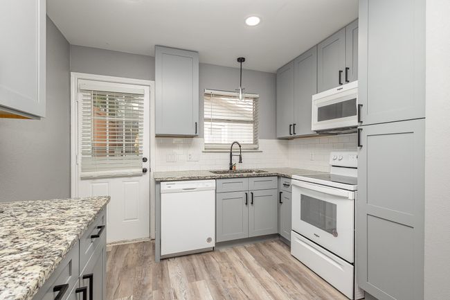 Kitchen with white appliances, gray cabinets, a sink, light wood-style flooring, and decorative backsplash | Image 17