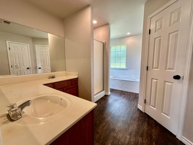 Full bathroom featuring wood finished floors, vanity, a shower stall, a garden tub, and recessed lighting | Image 10
