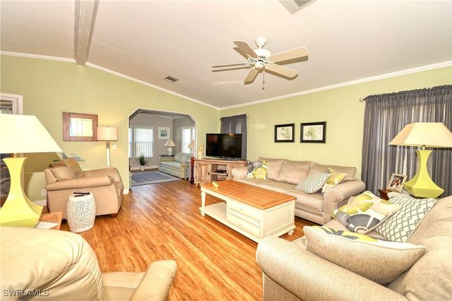Living room with crown molding, ceiling fan, hardwood / wood-style floors, and lofted ceiling with beams | Image 11