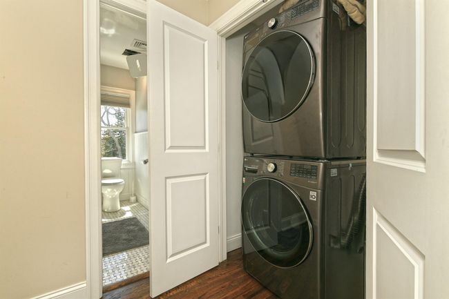Laundry room featuring stacked washer and clothes dryer, baseboards, dark wood-style flooring, and laundry area | Image 33
