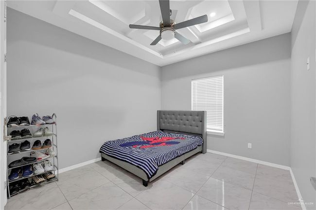 Bedroom featuring marble finish floors, a raised ceiling, and ceiling fan | Image 15