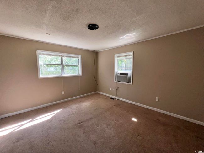 Carpeted empty room featuring plenty of natural light, a textured ceiling, cooling unit, baseboards, and crown molding | Image 13