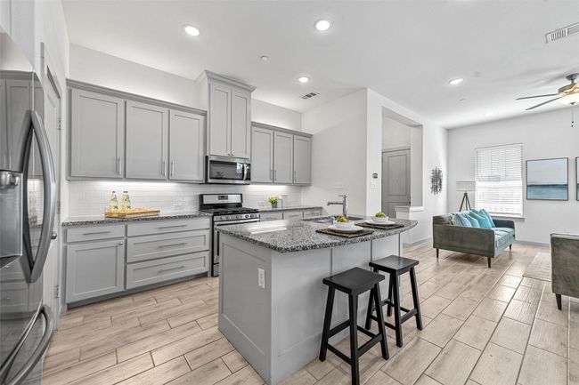 Kitchen featuring gray cabinetry, a kitchen breakfast bar, stainless steel appliances, and dark stone counters | Image 16