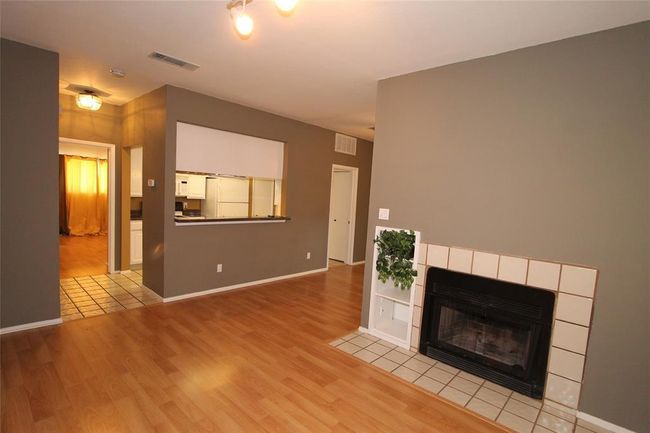 Unfurnished living room with wood finished floors, a tiled fireplace, and baseboards | Image 5