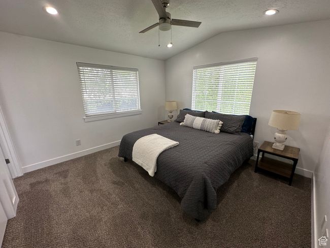 Carpeted bedroom with vaulted ceiling, multiple windows, baseboards, recessed lighting, and a ceiling fan | Image 22