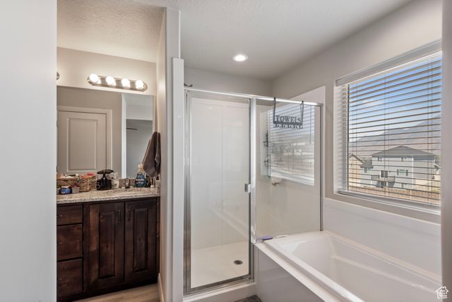 Full bath featuring a stall shower, a textured ceiling, vanity, and a bath | Image 10