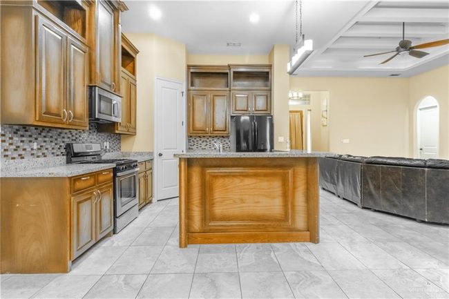 Kitchen with decorative light fixtures, stainless steel appliances, backsplash, and a kitchen island | Image 5