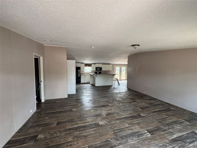 Unfurnished living room featuring dark wood finished floors and a textured ceiling | Image 5