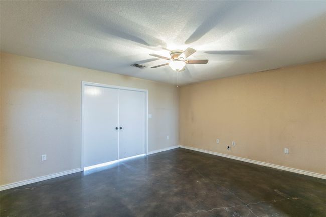 Unfurnished bedroom featuring a textured ceiling, visible vents, baseboards, a closet, and finished concrete floors | Image 14