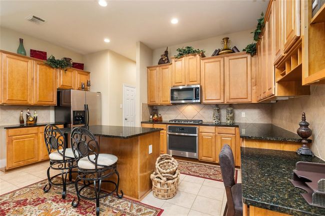 This kitchen is as functional as it is beautiful—imagine prepping dinner on the expansive countertops while chatting with family at the breakfast bar, or enjoying slow weekend mornings with the smell of fresh coffee filling the space. The stainless steel appliances, ample cabinetry, and thoughtful layout make it a true hub of the home. | Image 10
