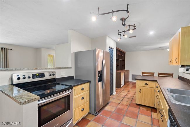 Kitchen featuring kitchen peninsula, track lighting, appliances with stainless steel finishes, and light tile patterned floors | Image 11