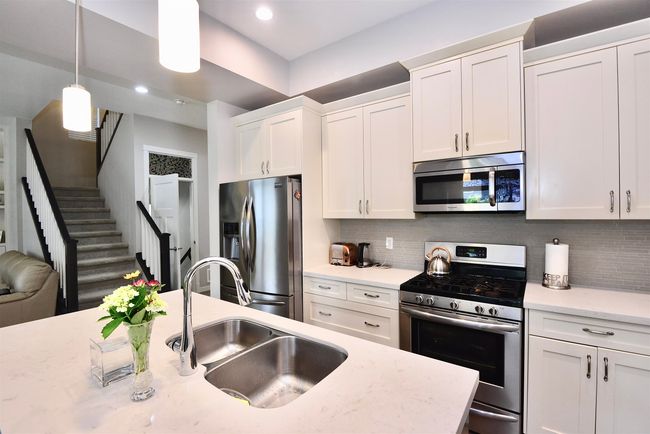 Kitchen with stainless steel appliances, white cabinetry, tasteful backsplash, hanging light fixtures, and recessed lighting | Image 6