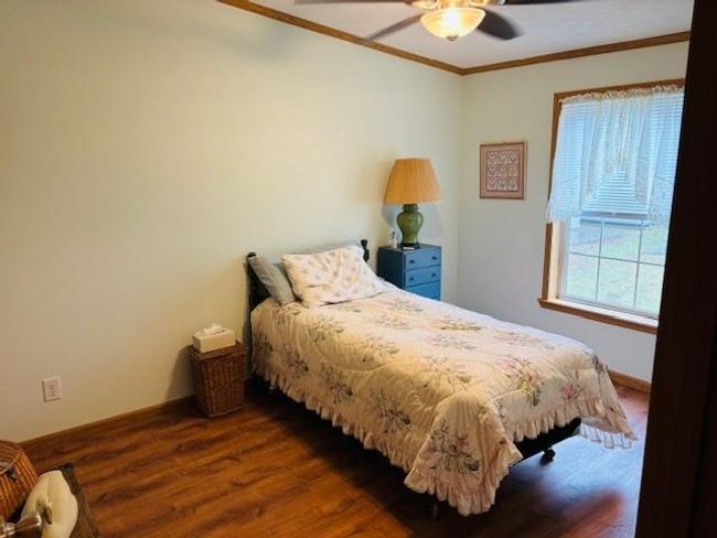 Bedroom with a ceiling fan, wood finished floors, baseboards, and ornamental molding | Image 10