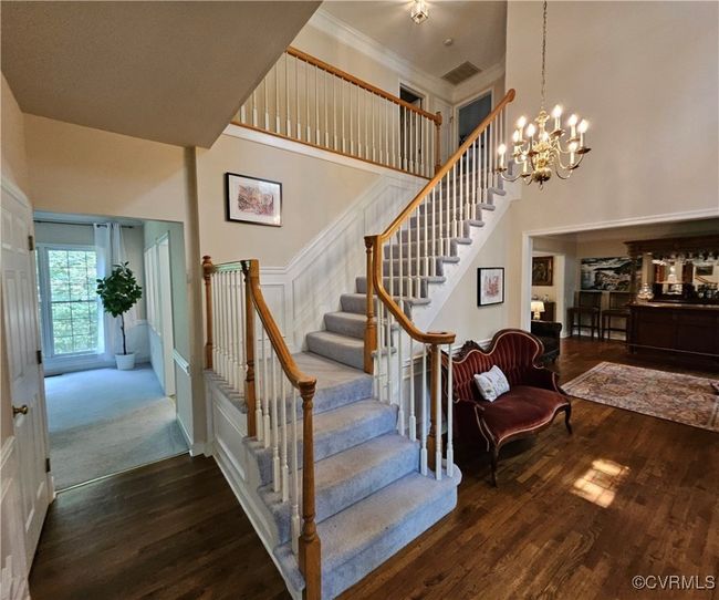 Stairs with wood finished floors, a towering ceiling, crown molding, w/picture frame wainscoting | Image 11