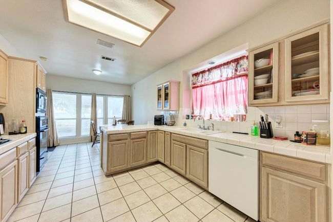 Kitchen with white dishwasher, a sink, black microwave, a peninsula, and decorative backsplash | Image 17