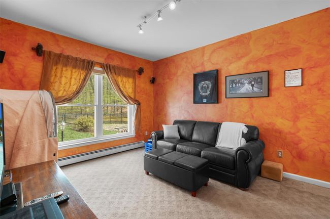 Living room with track lighting, baseboards, a baseboard radiator, and carpet flooring | Image 15