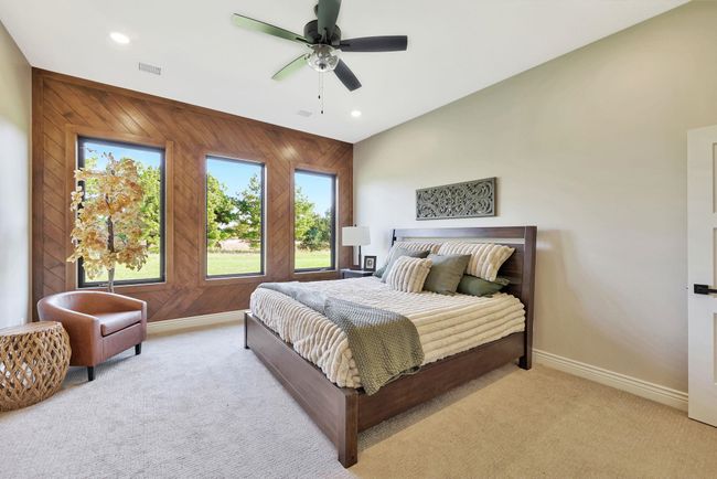 Carpeted bedroom with wood walls, ceiling fan, and multiple windows | Image 22