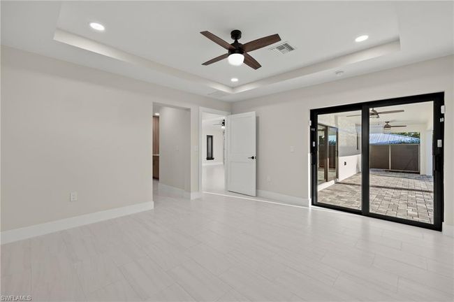 Empty room with ceiling fan, light tile patterned flooring, and a tray ceiling | Image 23